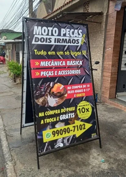 Cavalete de ferro dupla face instalado na calçada de uma loja de motopeças
