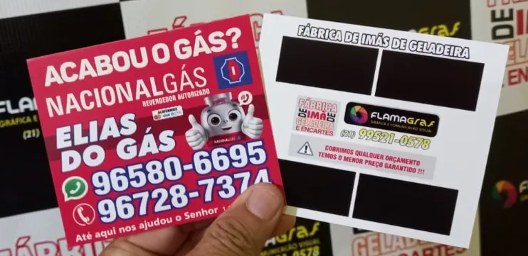 Ímã de geladeira de distribuidora de gás na mão, com o verso da Flamagraf ao lado